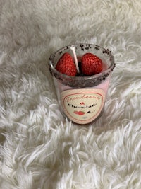 a candle with a cup of raspberries in it