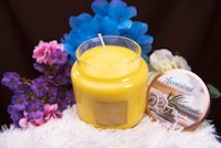 a yellow candle next to a jar of flowers