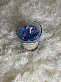 a small candle with blue and pink sprinkles on top of a white fur rug