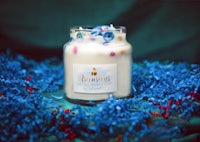 a jar of a candle sitting on top of a blue cloth