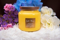 a jar with a yellow candle and flowers