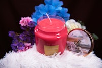 a pink candle next to a tin of flowers
