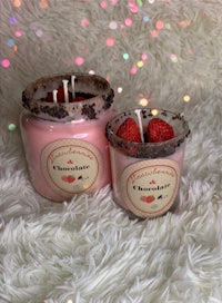two jars of strawberry scented candles on top of a fluffy blanket