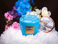 a blue candle with flowers and a candle next to it