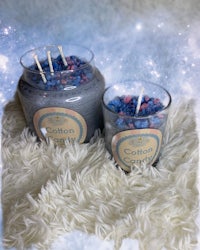 two jars of cotton scented candles on a fluffy blanket