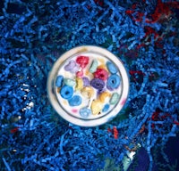 a jar of cereal is sitting on top of blue shredded paper