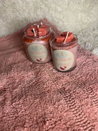 two pink candle jars on top of a pink blanket